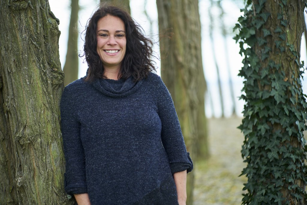 Lisa Meoli leaning against a tree on a windy day